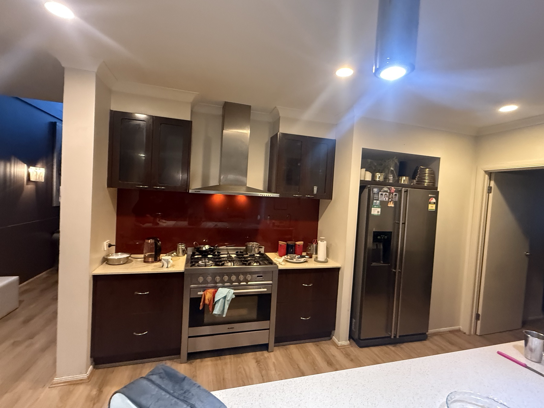 Original kitchen with dark cabinetry and a red splashback before the renovation
